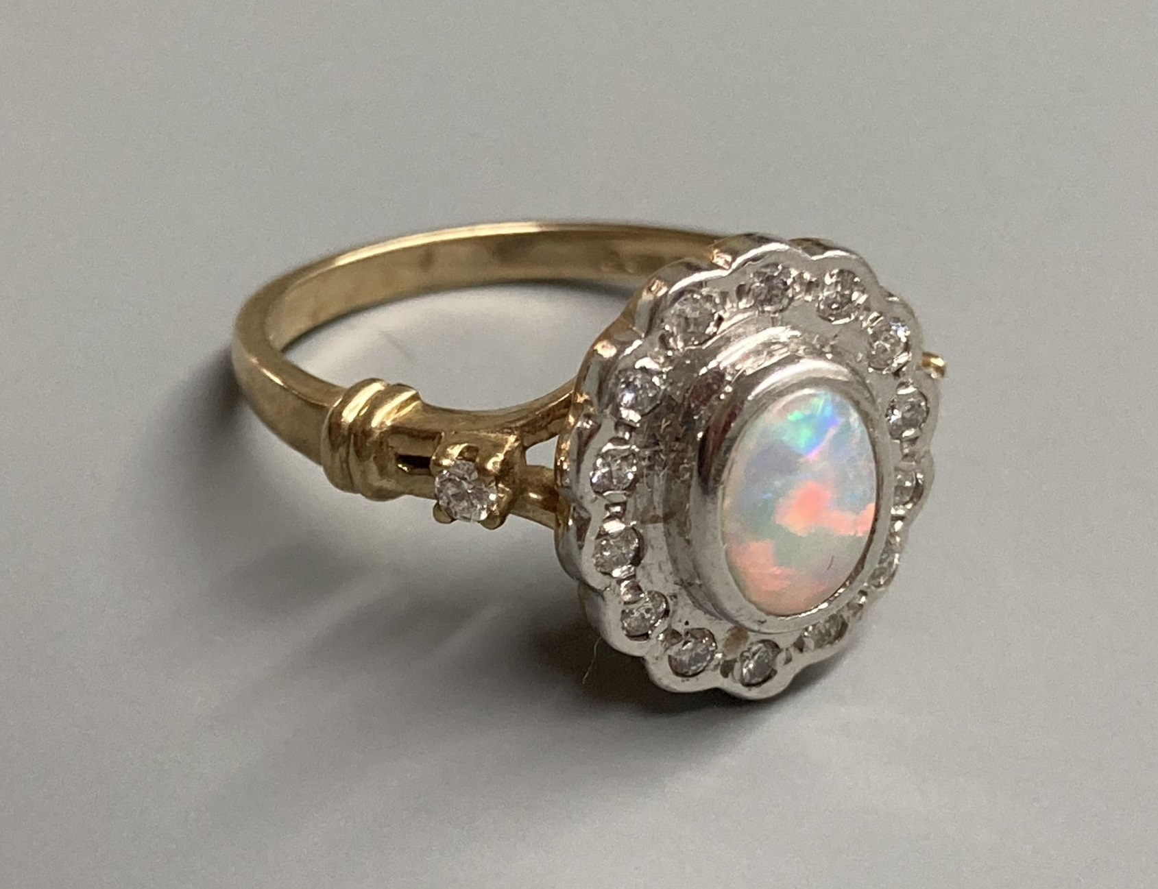 A modern 9ct gold, white opal and diamond chip set cluster ring, with diamond set shoulders, size O, gross 4.4 grams.